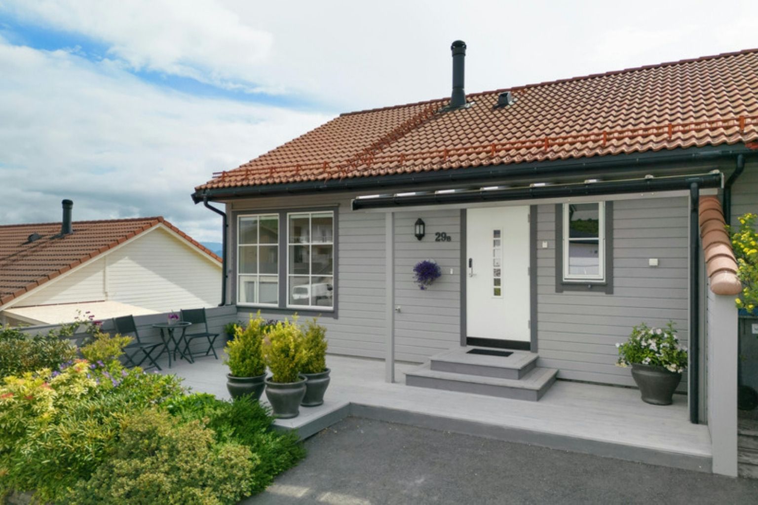 Lyst træhus med teglsten og en velholdt have